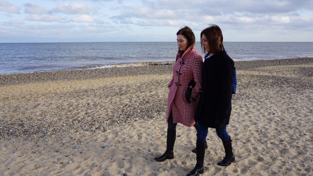 Jo Pontikos walking across a beach during a menopause coaching session